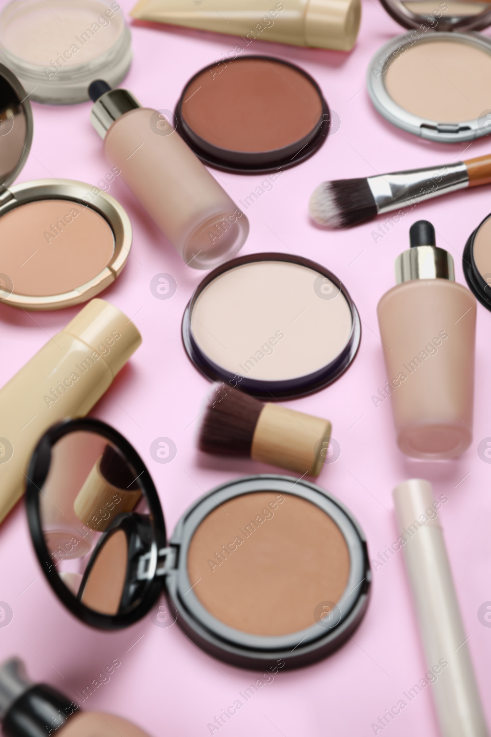 Photo of Face powders and other decorative cosmetic products on pink background