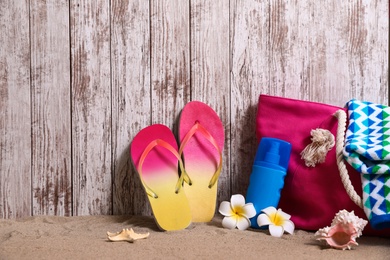 Photo of Composition with stylish summer beach accessories on sand near wooden wall. Space for text