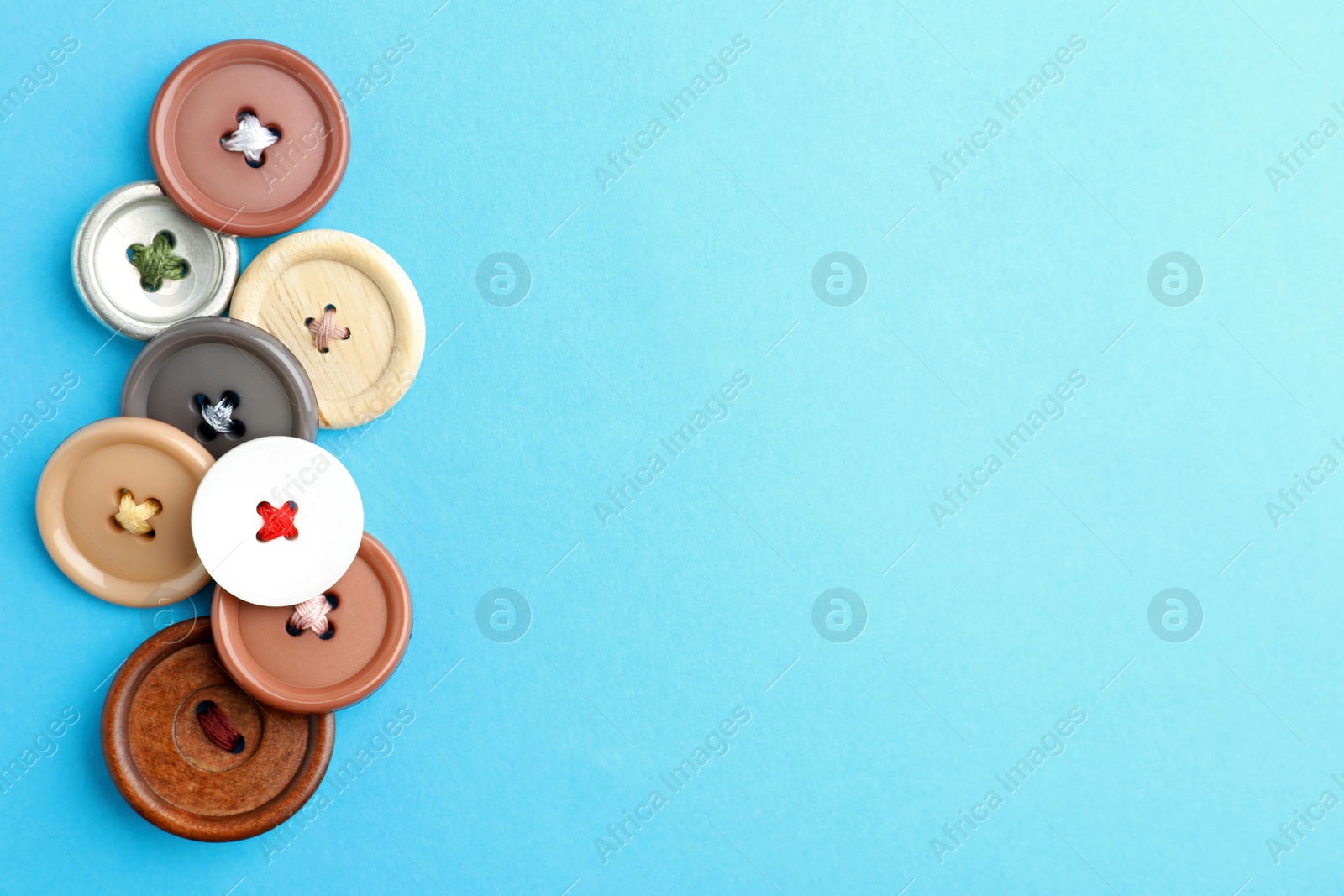 Photo of Many colorful sewing buttons on light blue background, flat lay. Space for text