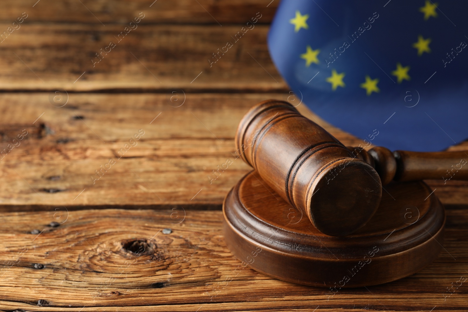 Photo of Judge's gavel and European Union flag on wooden table. Space for text