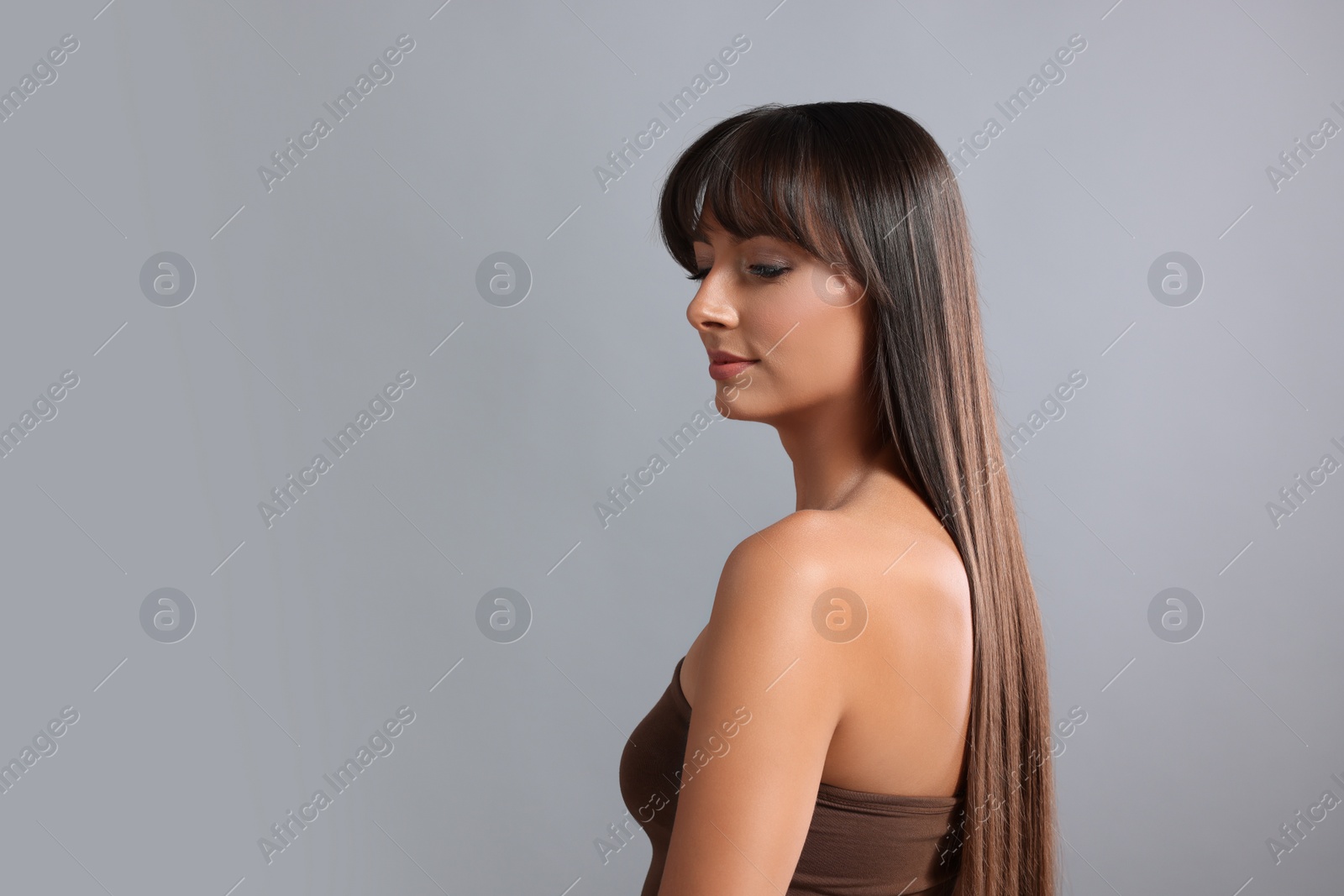 Photo of Hair styling. Beautiful woman with straight long hair on grey background, space for text