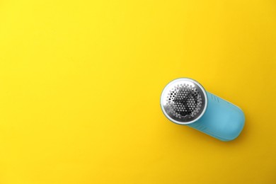 Photo of Modern fabric shaver on yellow background, top view. Space for text