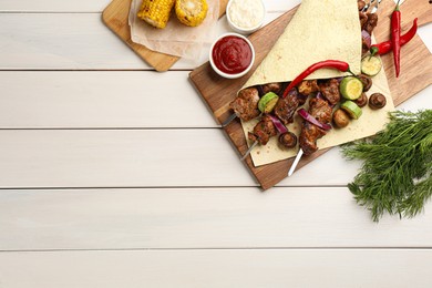 Metal skewers with delicious meat and vegetables served on white wooden table, flat lay. Space for text