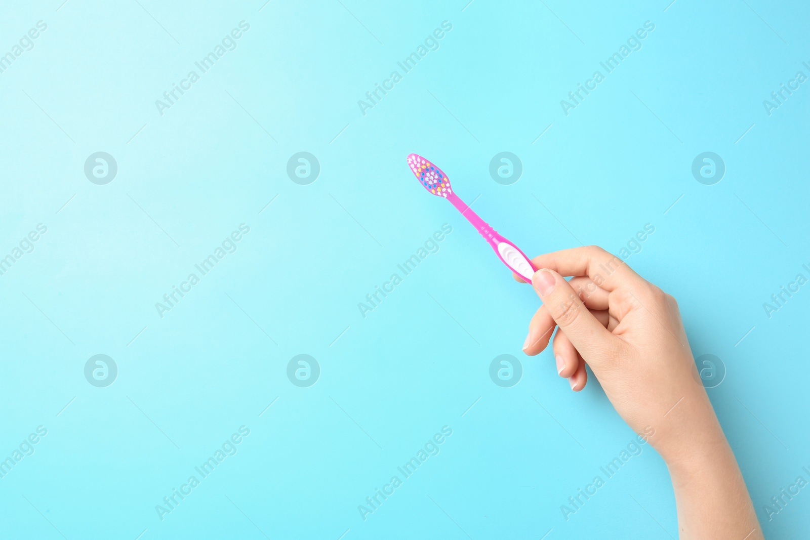 Photo of Woman holding manual toothbrush against color background