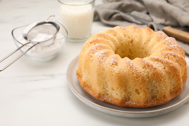 Photo of Delicious sponge cake with powdered sugar and glass of milk on white table, closeup