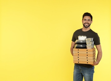 Photo of Young courier with different orders on color background, space for text. Food delivery service