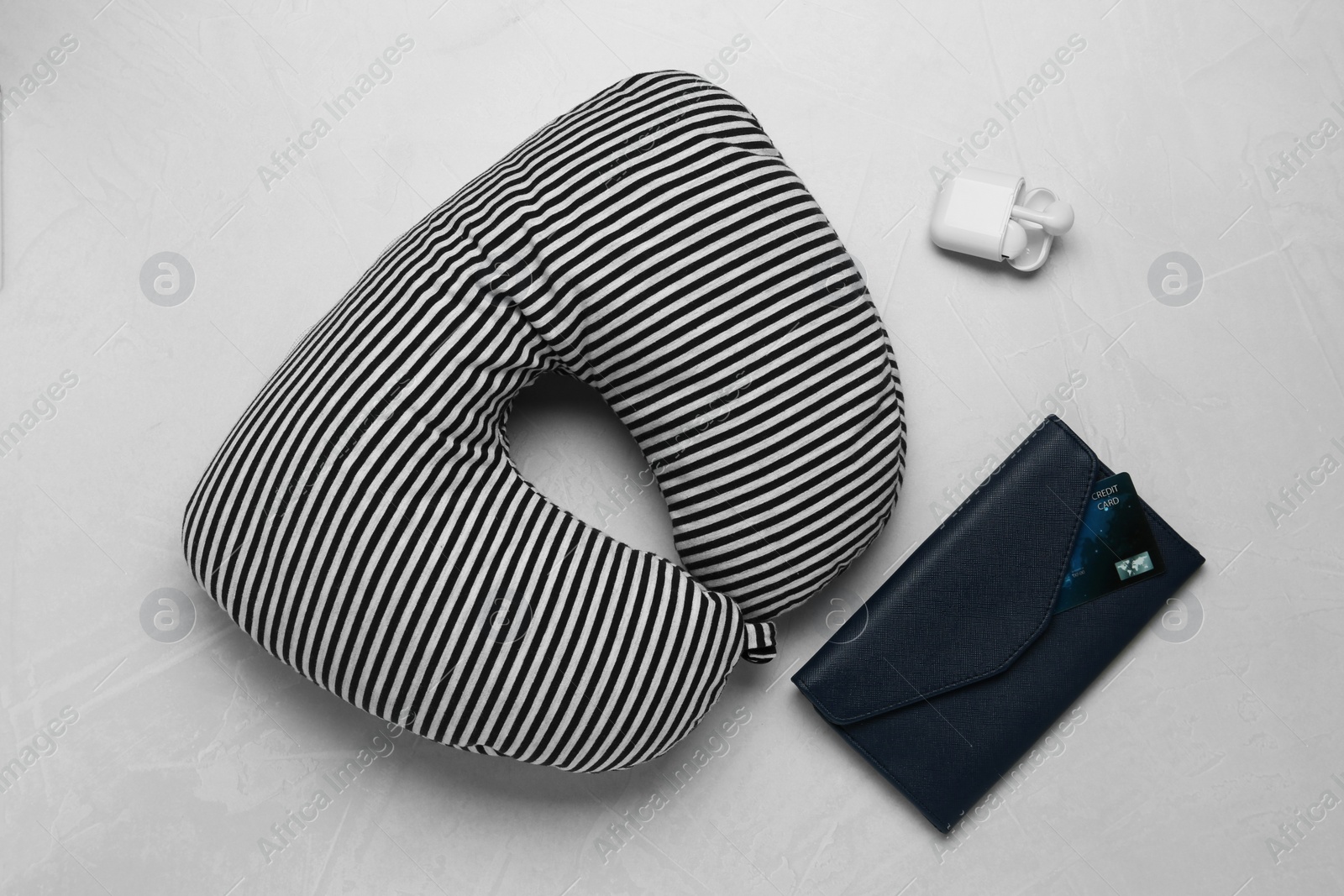 Photo of Striped travel pillow, wallet with credit card and earphones on gray background, flat lay