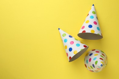 Beautiful party hats on yellow background, top view. Space for text