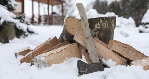 Photo of Axe, chopped wood and wooden log outdoors on winter day