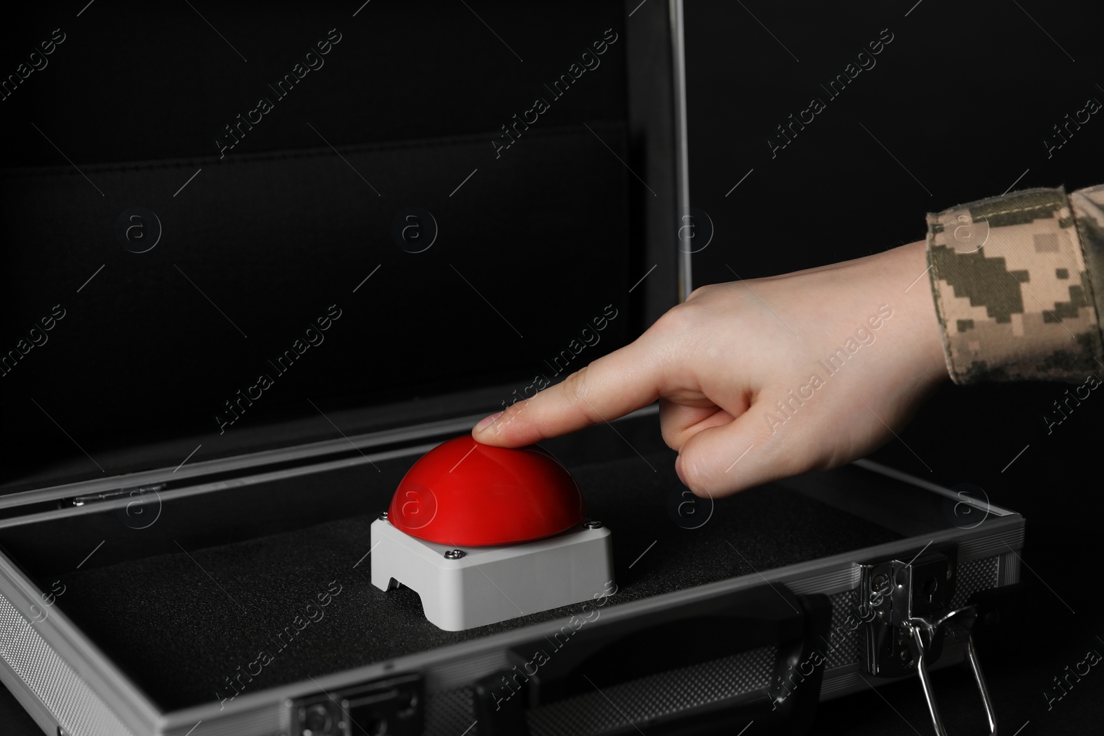 Photo of Serviceman pressing red button of nuclear weapon at black table, closeup. War concept