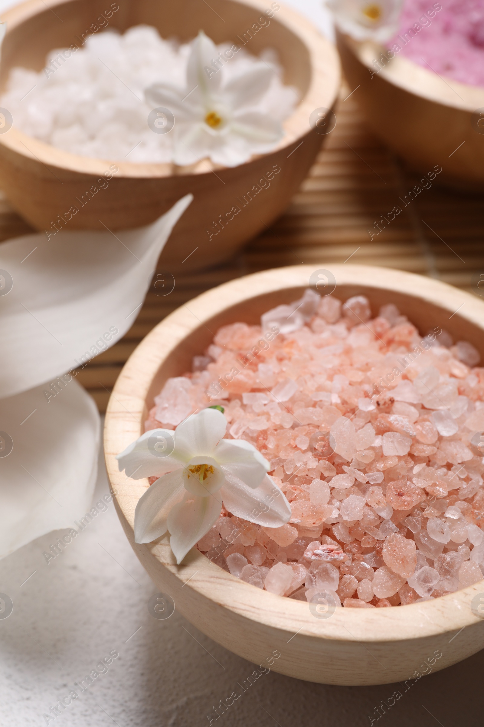 Photo of Different types of sea salt and flowers on light table, selective focus. Spa products