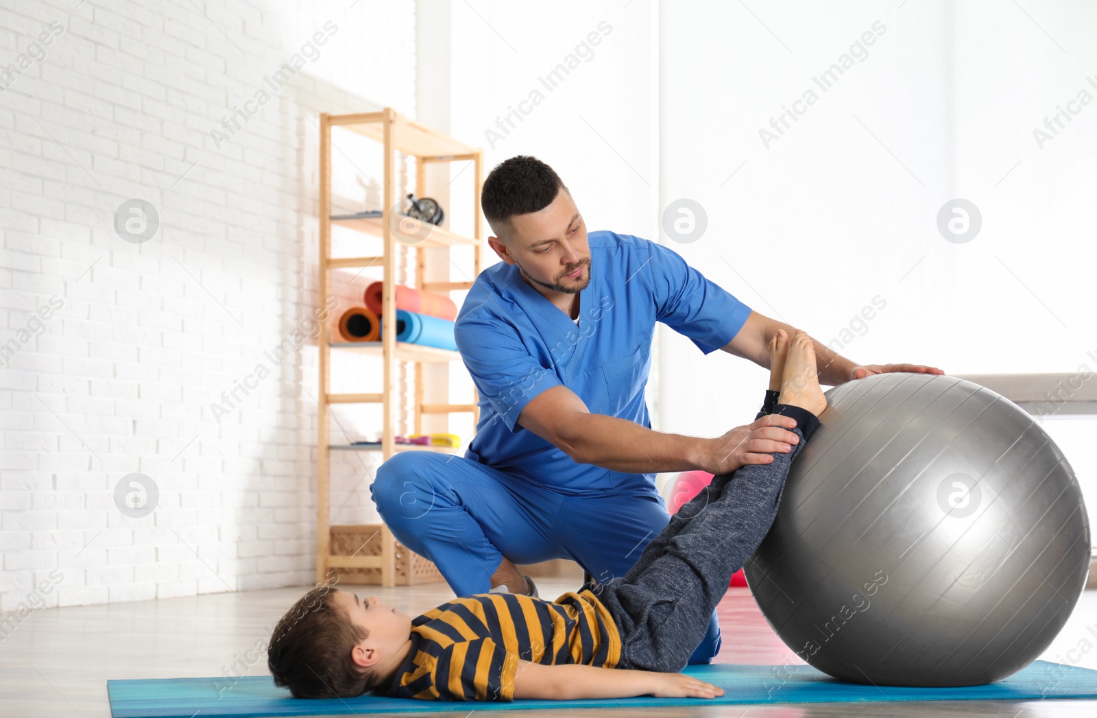 Photo of Orthopedist working with little boy in hospital gym