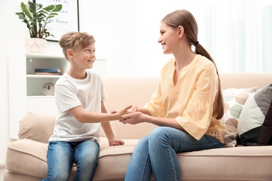 Young woman checking little boy's pulse indoors