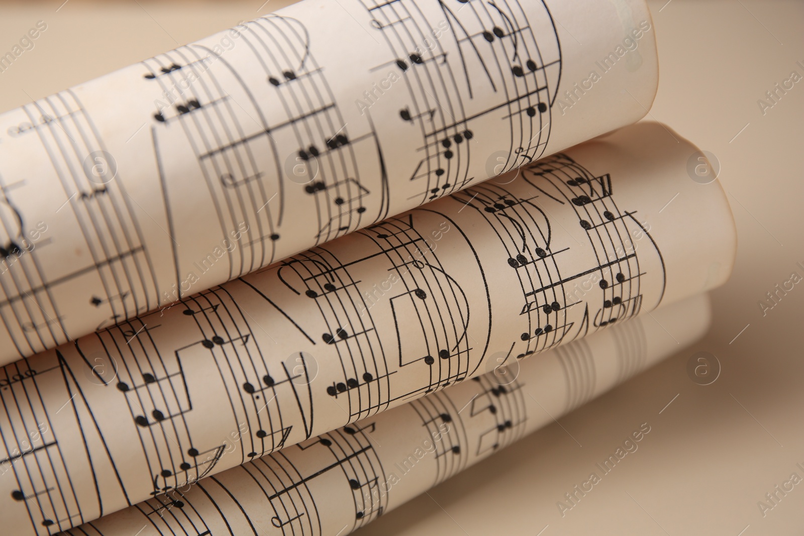 Photo of Rolled sheets with music notes on light background, closeup