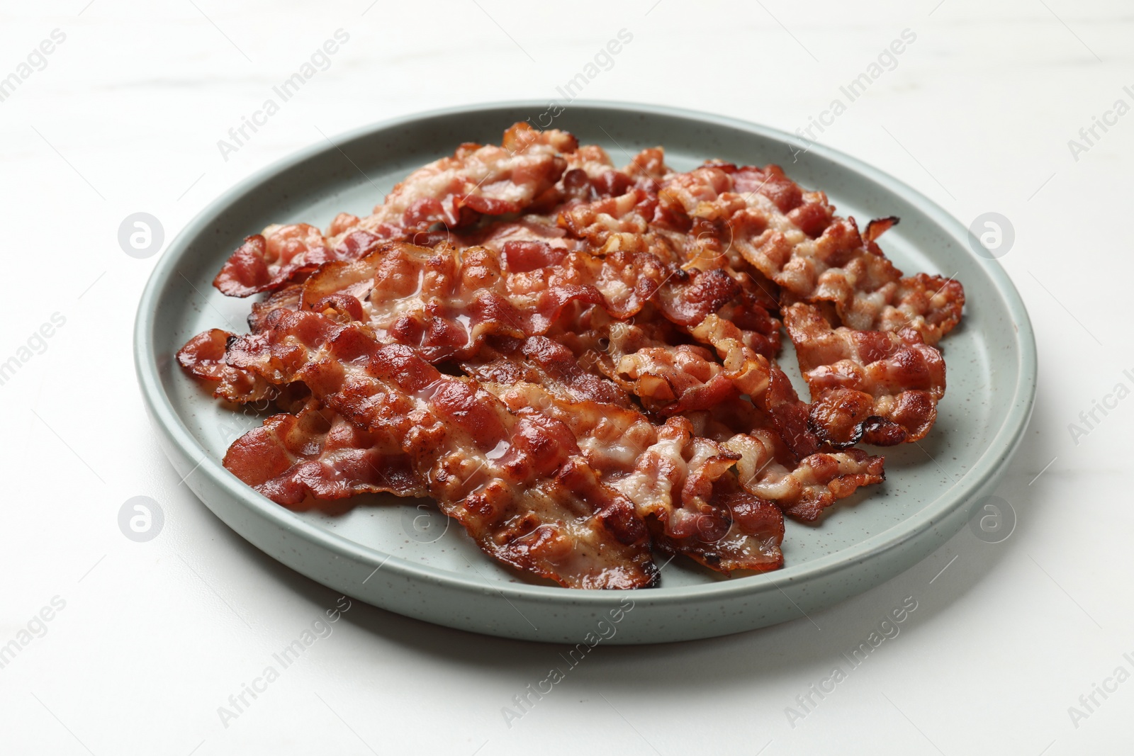 Photo of Slices of tasty fried bacon on white table