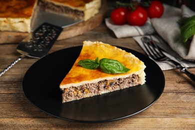 Piece of delicious pie with minced meat on wooden table