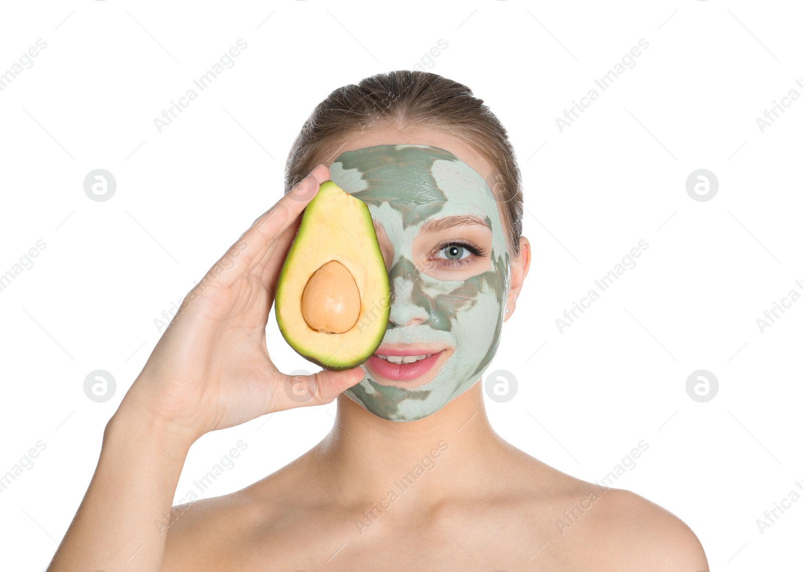 Photo of Beautiful woman holding avocado near her face with clay mask on white background