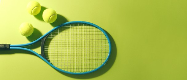 Tennis racket and balls on green background, flat lay. Banner design with space for text