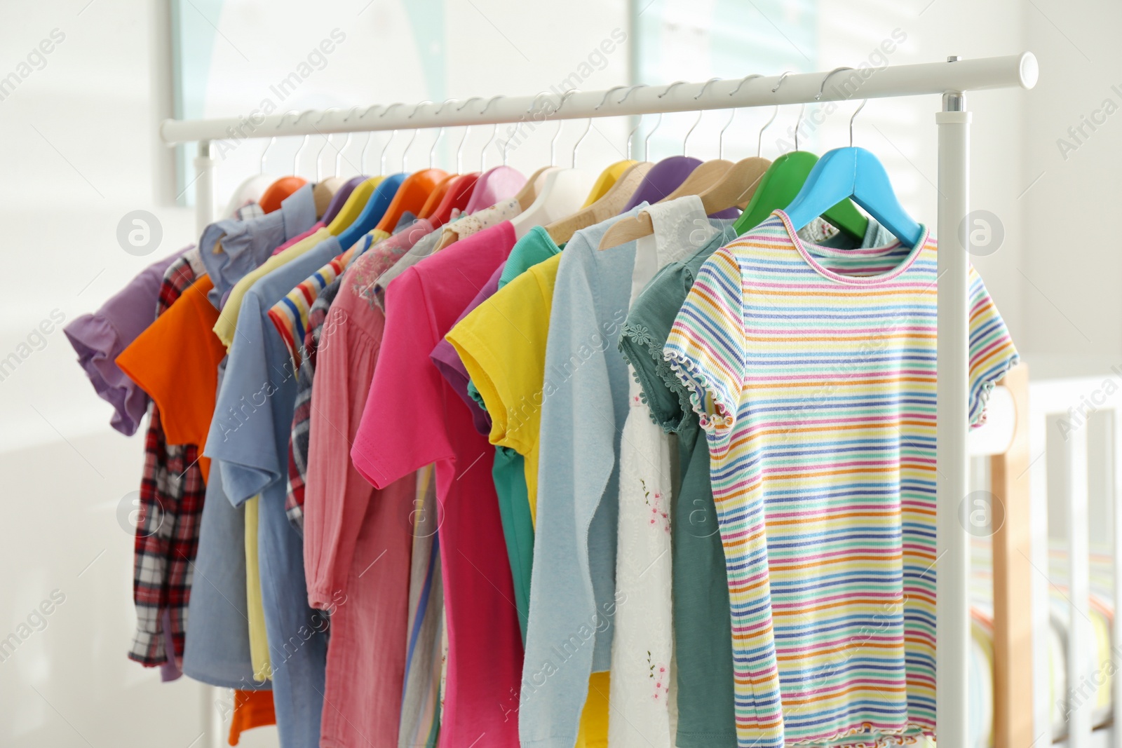 Photo of Different child's clothes hanging on rack indoors, closeup