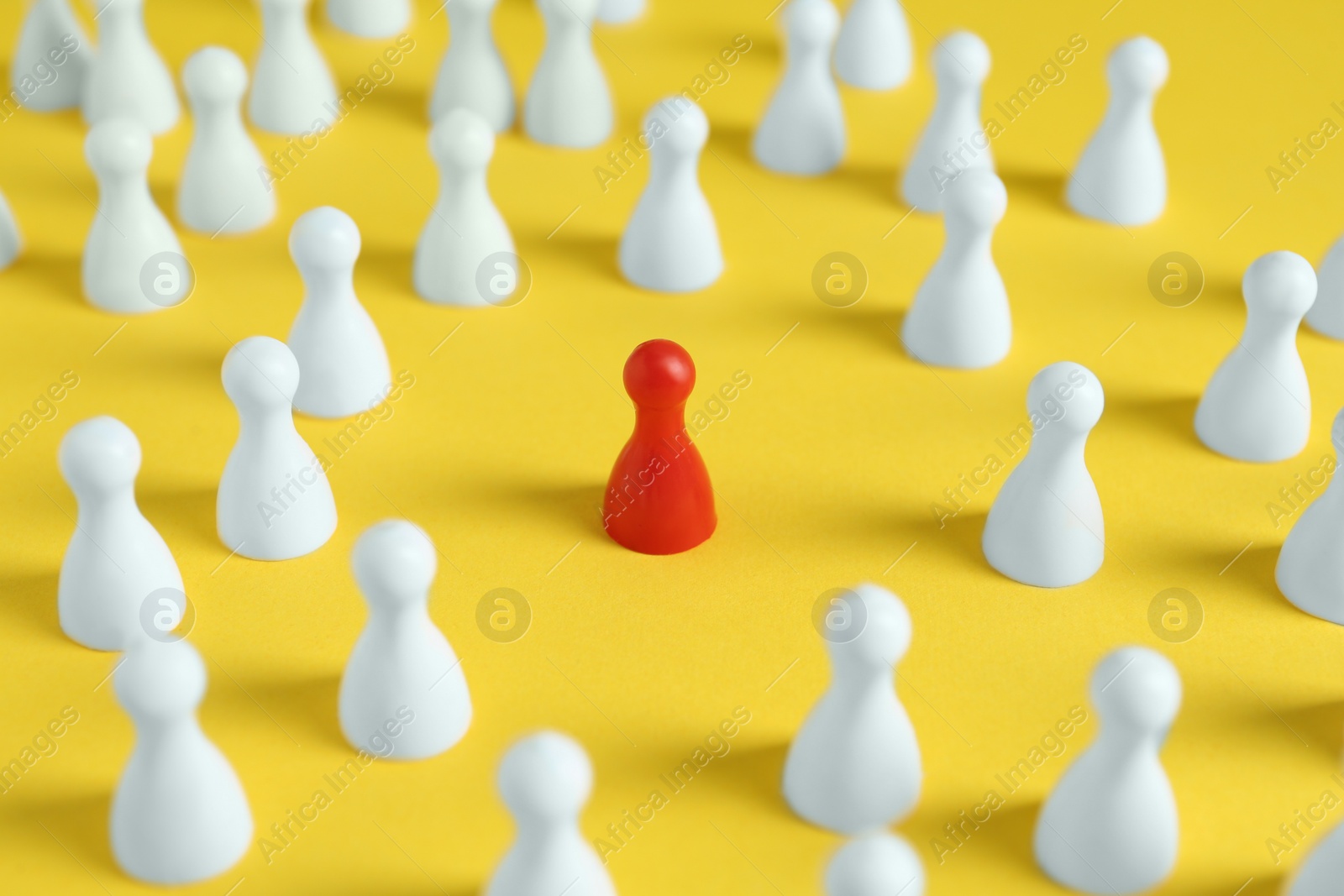 Photo of One red pawn among others on yellow background. Social inclusion concept