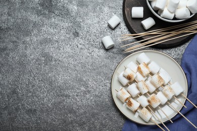 Photo of Sticks with roasted marshmallows on grey table, flat lay. Space for text