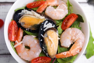 Photo of Bowl of delicious salad with seafood on white wooden table, top view