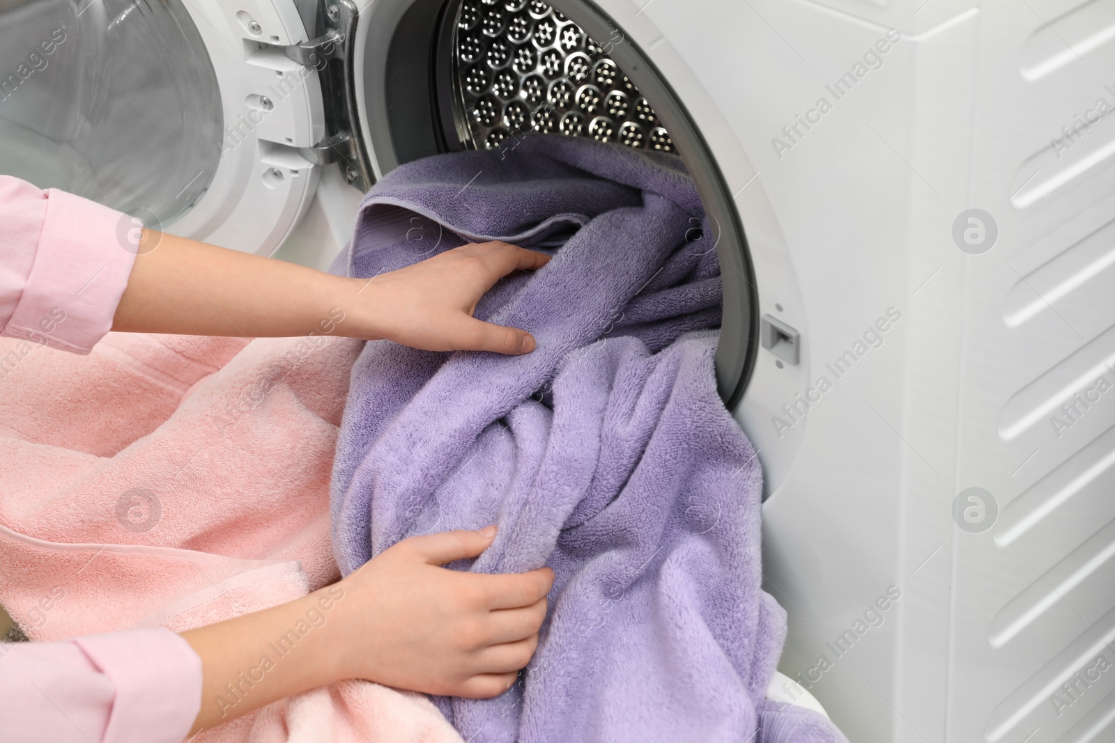 Photo of Woman taking towels out of washing machine in laundry room