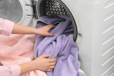 Woman taking towels out of washing machine in laundry room