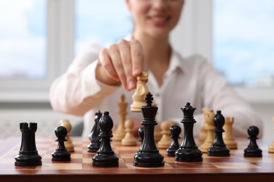 Photo of Woman playing chess during tournament at chessboard indoors, closeup