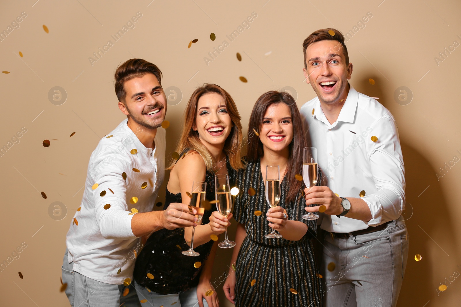 Photo of Portrait of happy friends with champagne in glasses and confetti on color background