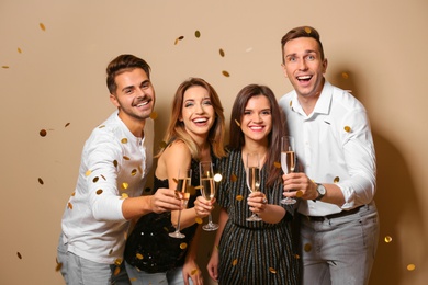 Portrait of happy friends with champagne in glasses and confetti on color background