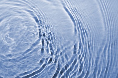 Rippled surface of clear water on light blue background, closeup