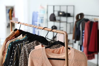 Photo of Different stylish clothes on rack in dressing room, closeup