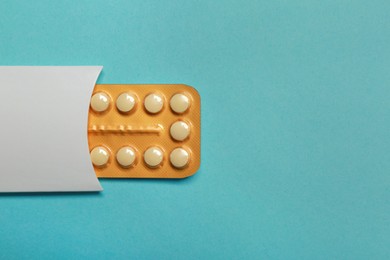 Birth control pills on light blue background, top view. Space for text