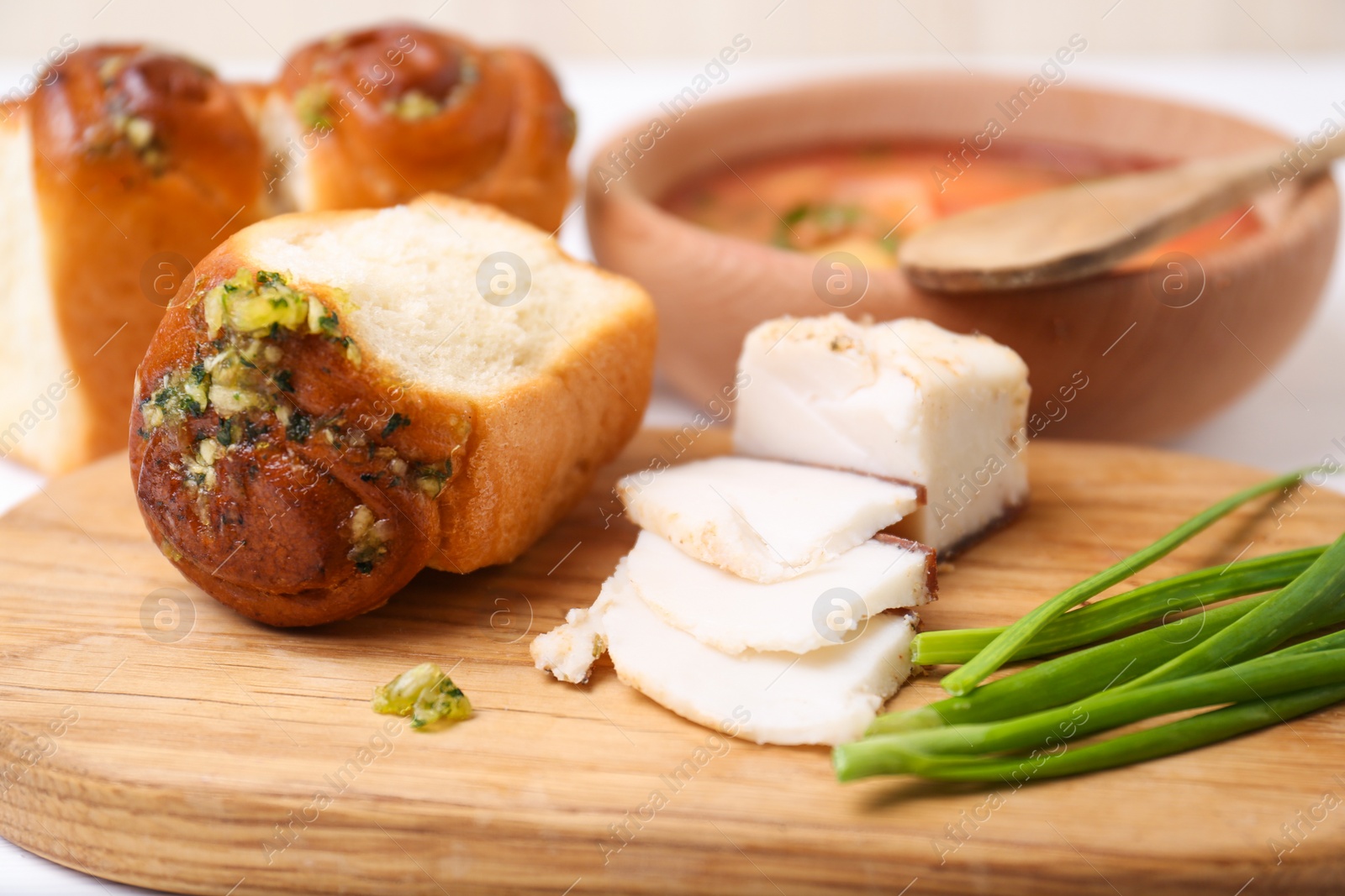 Photo of Delicious pampushky (buns with garlic), green onions and salo served for borsch on table, closeup. Traditional Ukrainian cuisine