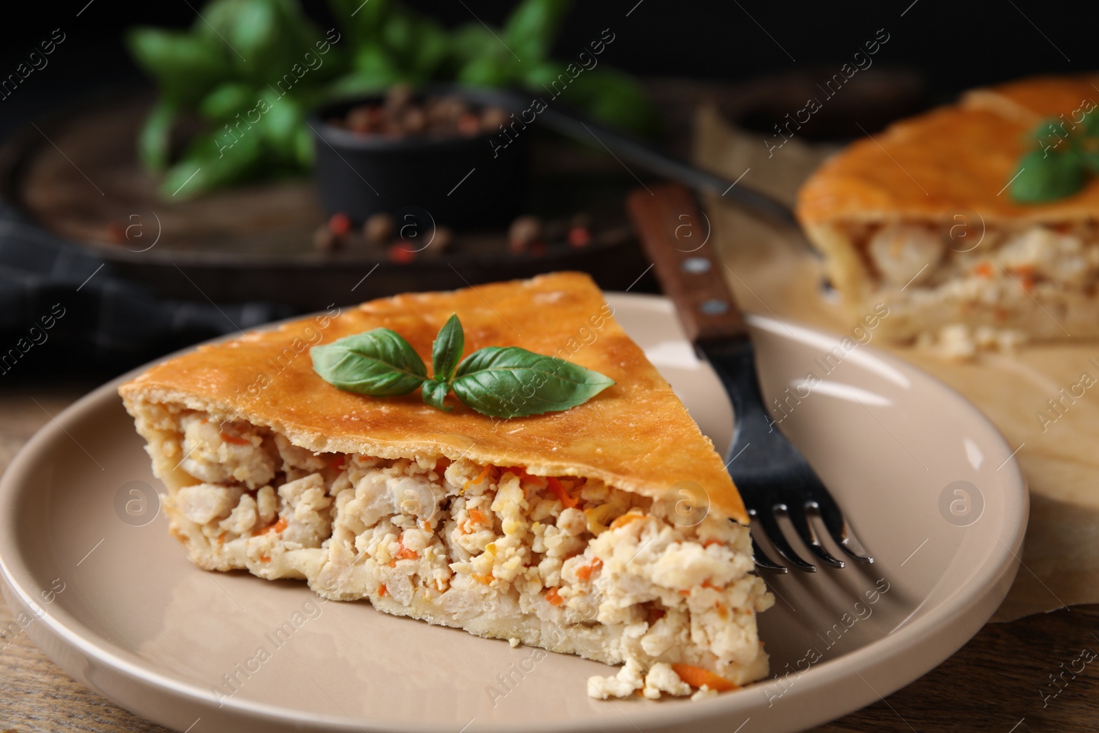Photo of Piece of delicious pie with meat and basil on wooden table, closeup