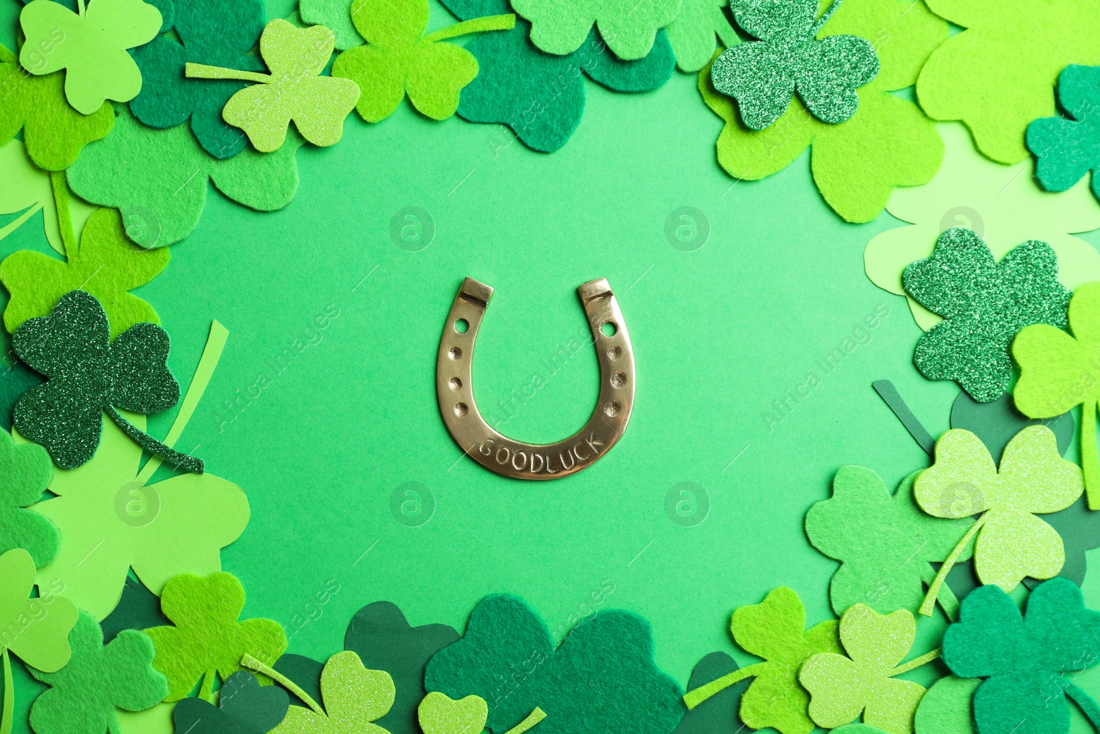 Photo of Flat lay composition with clover leaves and horseshoe on green background. St. Patrick's day