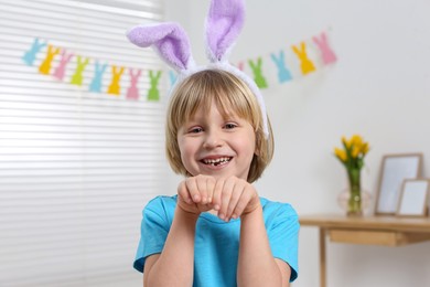 Happy boy wearing bunny ears indoors. Easter celebration