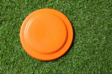 Photo of Orange plastic frisbee disk on green grass, top view
