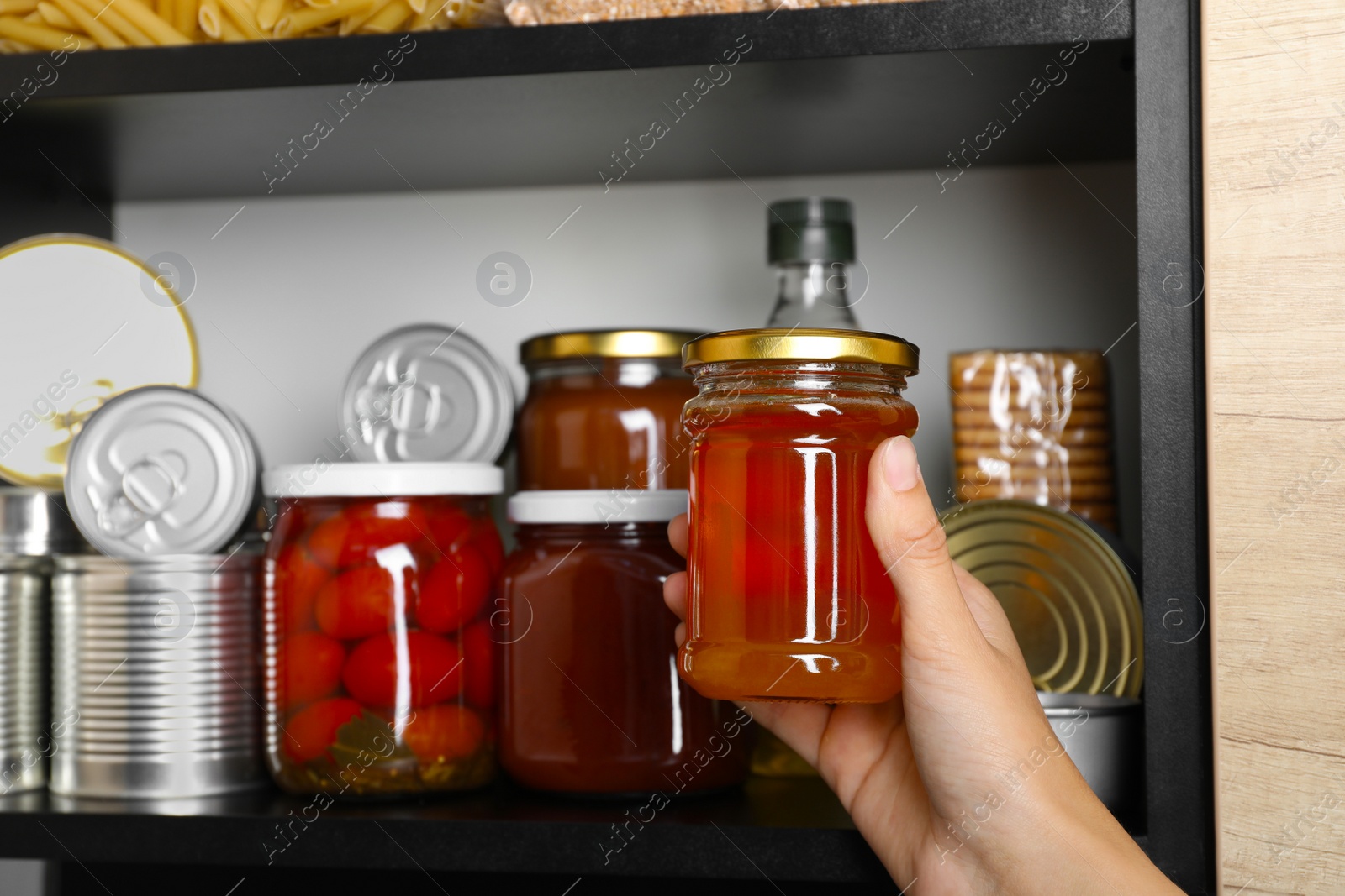Photo of Woman with jar of honey near shelf indoors, closeup and space for text. Food donation