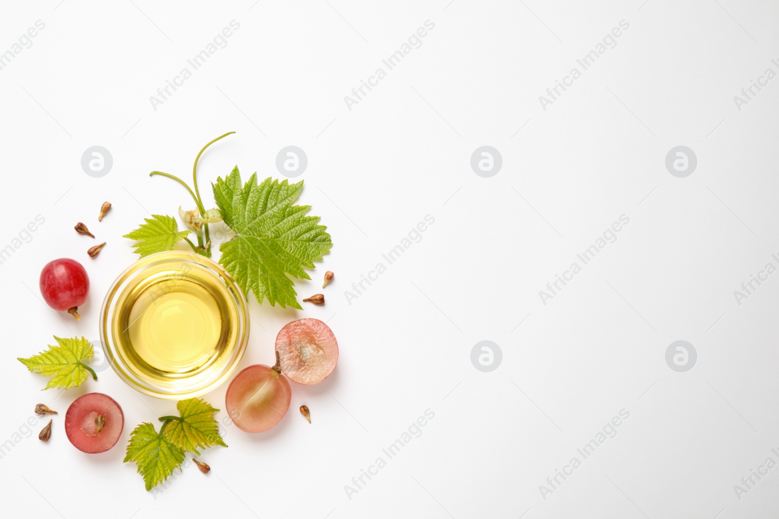 Photo of Composition with bowl of natural grape seed oil on white background, top view. Organic cosmetic