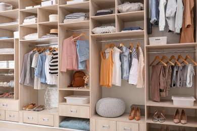 Photo of Stylish clothes, shoes and home stuff in large wardrobe closet