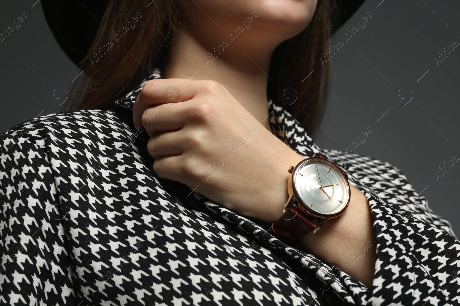 Photo of Woman wearing luxury wristwatch on grey background, closeup