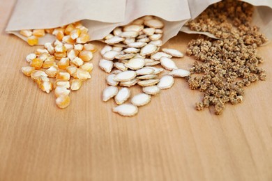 Photo of Different vegetable seeds on wooden table, closeup