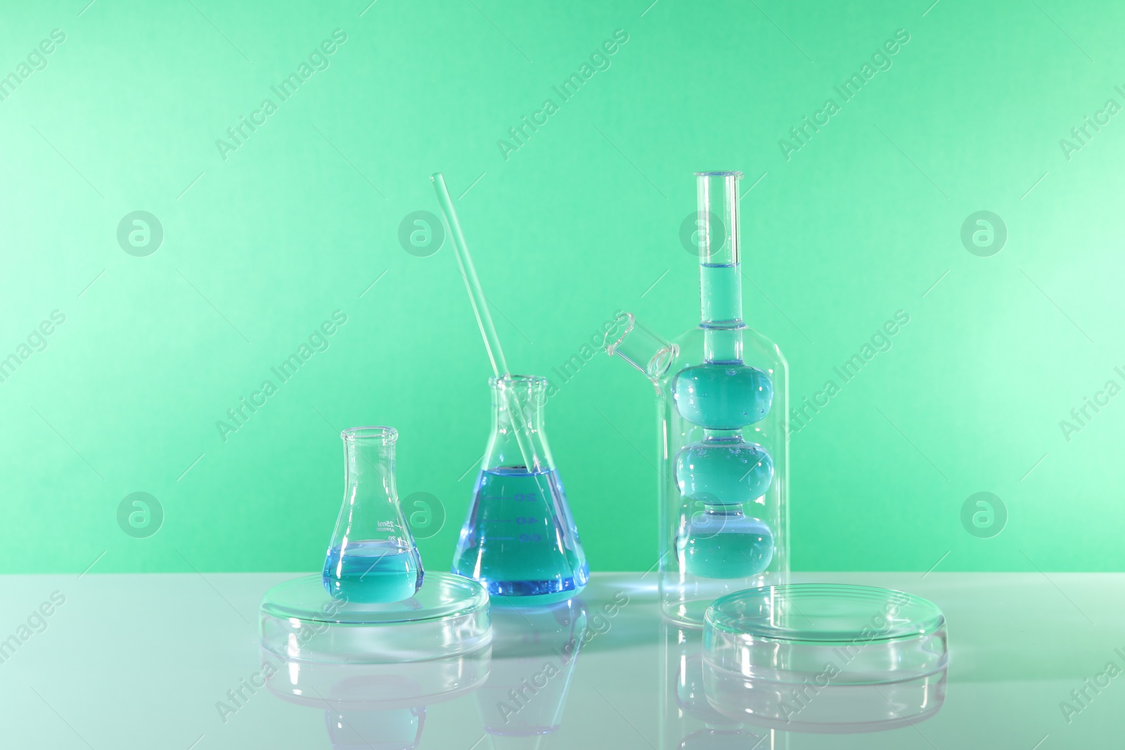 Photo of Laboratory analysis. Different glassware on table against green background