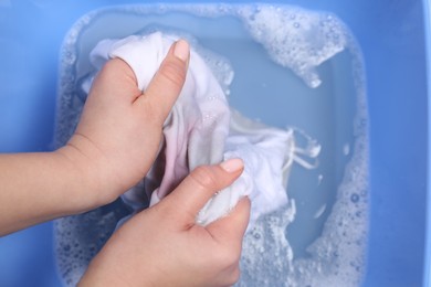 Woman washing white garment with stain, top view