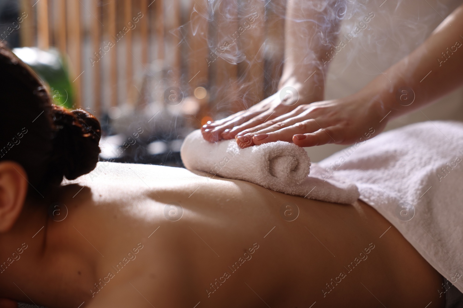 Photo of Spa therapy. Beautiful young woman lying on table during hot towel massage in salon, closeup