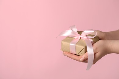 Photo of Woman holding gift box with bow on pink background, closeup. Space for text