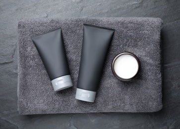 Photo of Set of men's cosmetic products with towel on grey stone table, top view