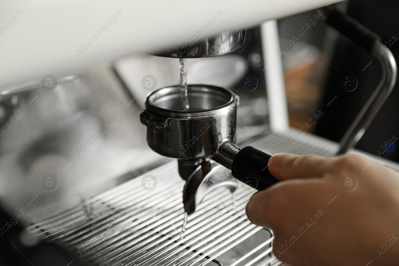 Photo of Barista cleaning portafilter at coffee machine in cafe, closeup